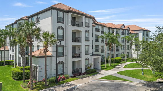 Front view of a multi-story residential building with balconies and tiled roofs.