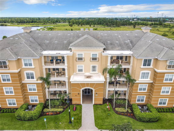 Front view of a multi-story apartment building with balconies and a tiled roof.