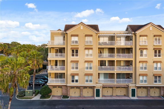 Front view of a multi-story apartment building with balconies and a tiled roof.