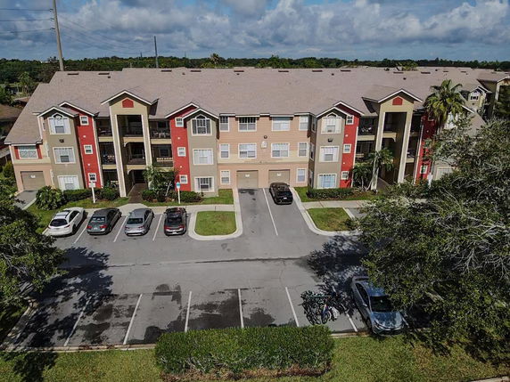 Front view of a multi-story apartment building with parking spaces in front.