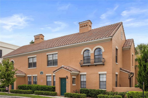 Front view of a two-story house with a tiled roof and arched windows.