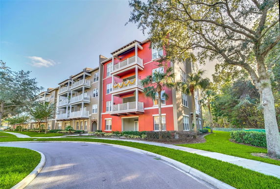 Front view of a multi-story apartment building with balconies and red exterior accents.