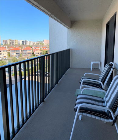 Balcony with seating and a view of surrounding residential area and buildings.