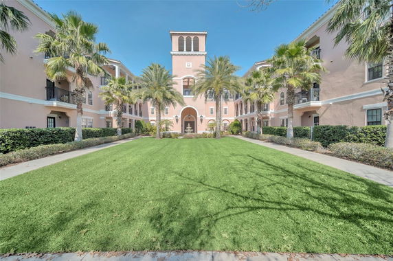 Front view of a large multi-story building with a central tower and palm trees.