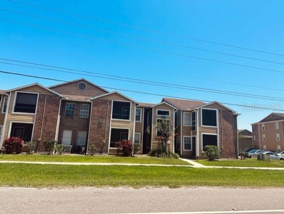 Front view of a multi-story apartment building with brick and siding exterior.