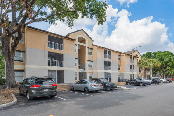Front view of a multi-story apartment building with a parking area in front.