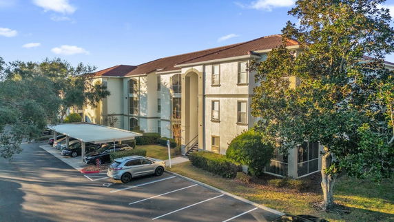 Front view of a multi-story building with covered parking area.