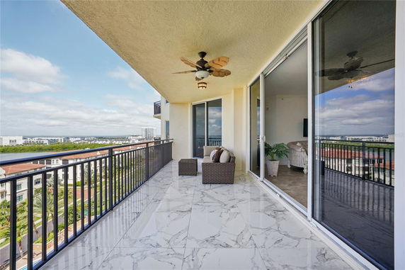 Balcony view with marble flooring and outdoor seating, overlooking cityscape and sky.