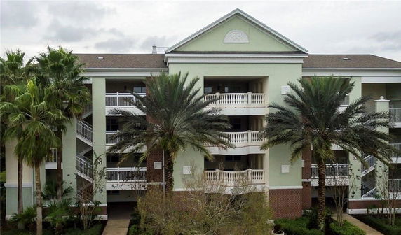 Front view of a multi-story building with balconies and a sloped roof.