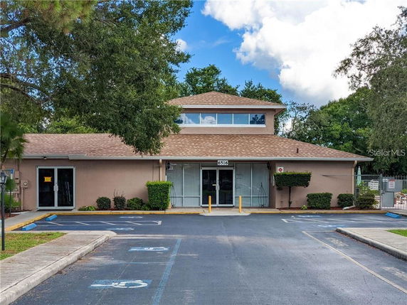 Front view of a building with a hip roof and parking area in front.