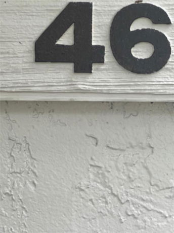 Partial view of a building with the number 46 on its exterior wall.