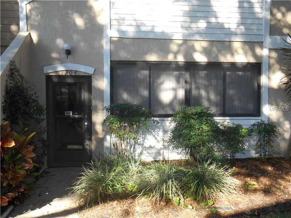 Front view of a two-story building entrance with a door and large window.