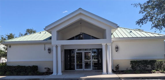 Front view of a building with a green metal roof and white columns.