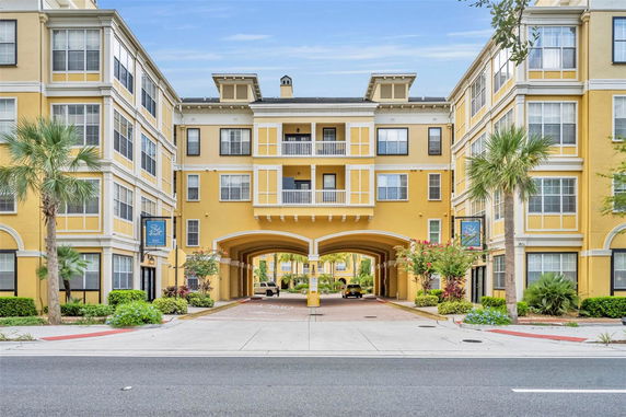 Front view of a multi-story building with an archway entrance and yellow exterior.