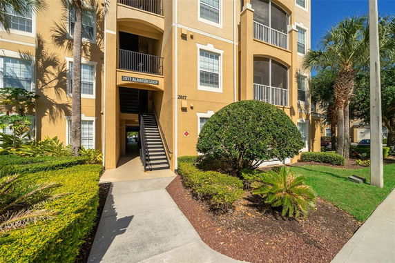 Front view of a multi-story apartment building with an exterior staircase and balconies.