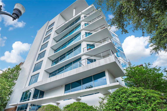 Front view of a modern multi-story building with large glass windows and balconies.