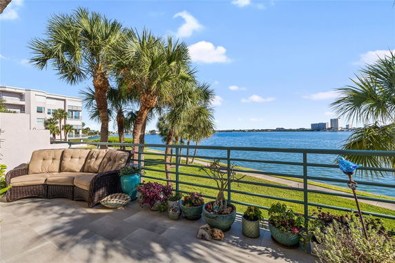 Panoramic view from a patio overlooking a water body with buildings in the distance.