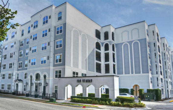 Front view of a multi-story apartment building with a gated entrance and arched accents.