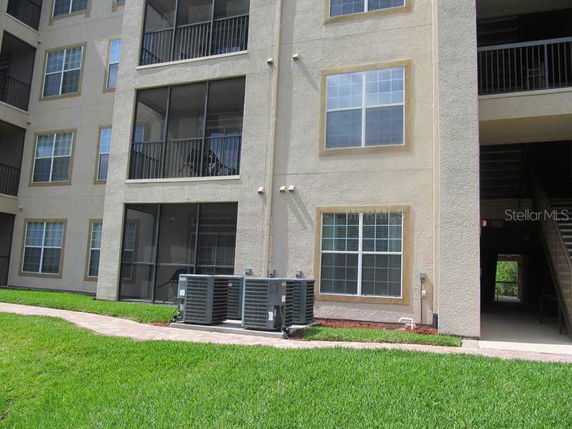 Front view of a multi-story apartment building with balconies and visible air conditioning units.
