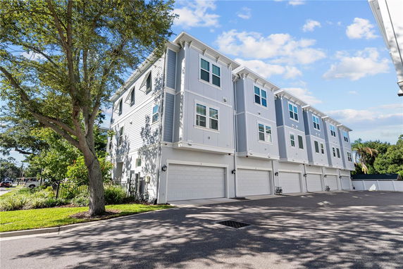 Front view of a row of three-story townhouses with garage doors on the ground level.