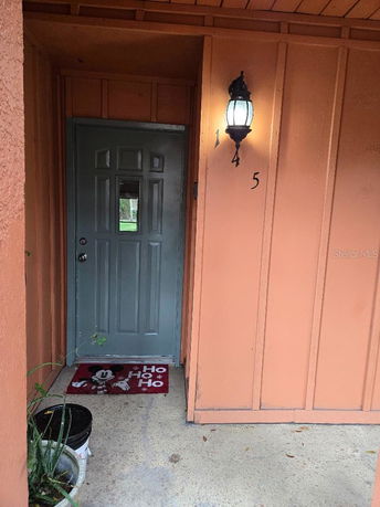Front view of a house entrance with an orange wall and a gray door.
