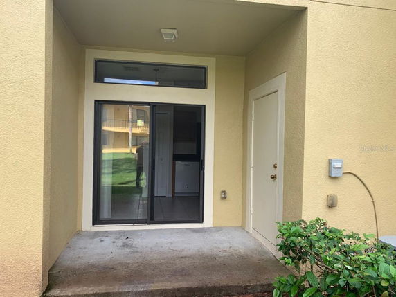 Front entrance of a building with a sliding glass door and a small porch area.