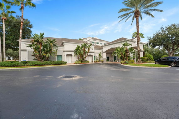 Front view of a building with a large driveway and tropical plants.