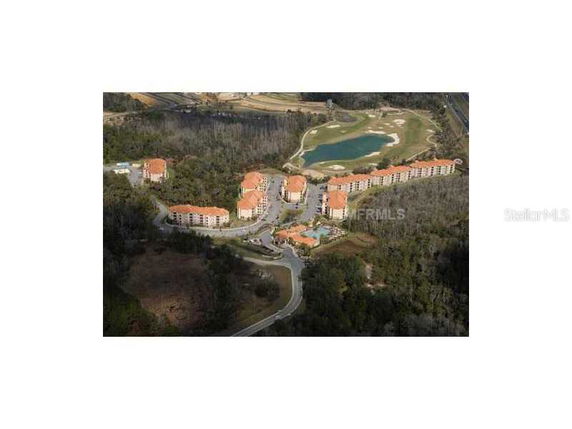 Aerial view of a residential complex with multiple buildings and a body of water nearby.