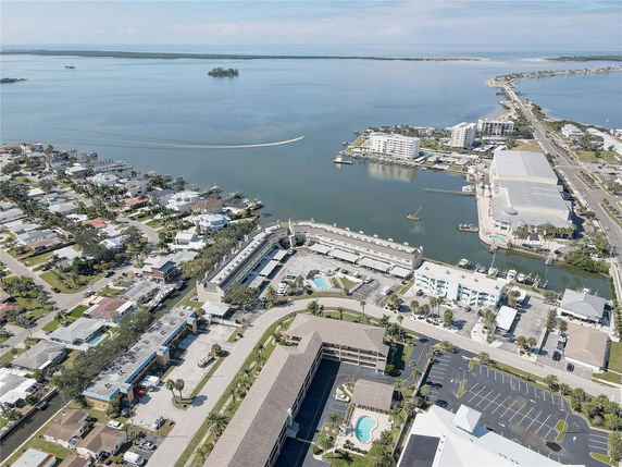 Aerial view of a coastal area with residential buildings, roads, and a water body.