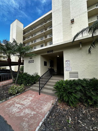 Front view of a multi-story residential building with exterior balconies and numbered entrance.