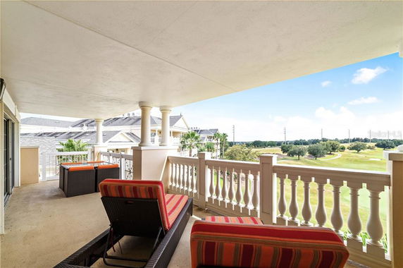 Covered balcony with seating overlooking a landscaped area and golf course.