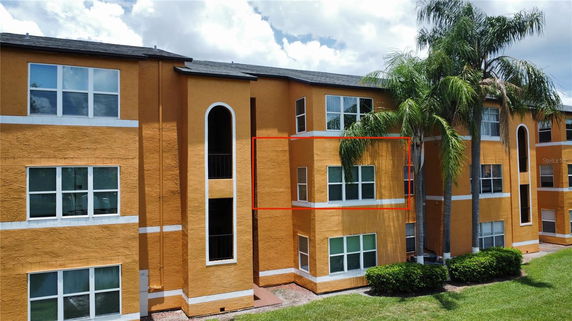 Front view of a multi-story apartment building with orange exterior and white window frames.