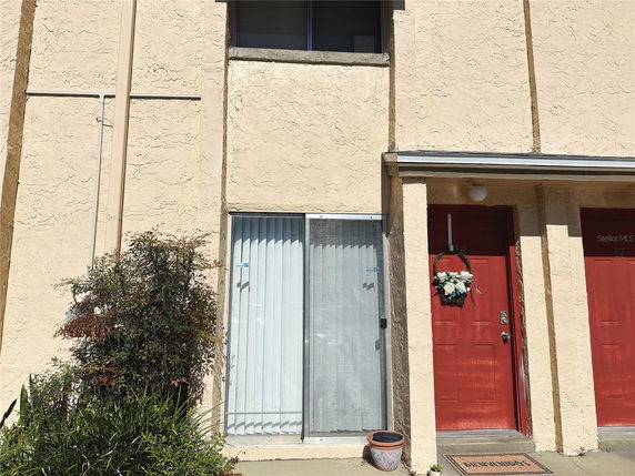 Front view of a townhouse with beige stucco walls and red doors.