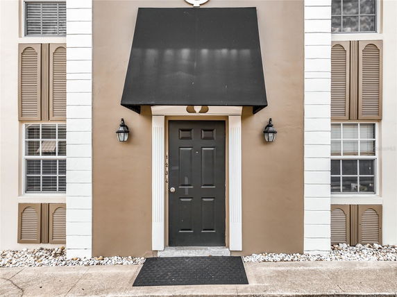 Front view of a building entrance with a black door and an awning.