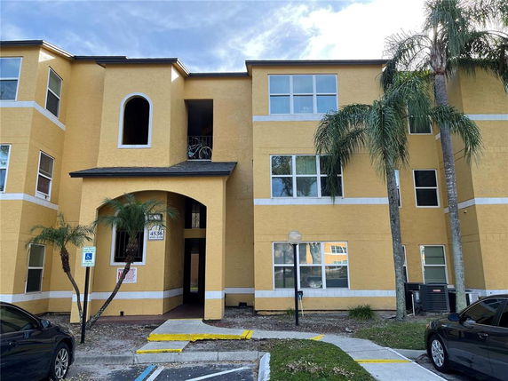 Front view of a yellow multi-story apartment building with an arched entrance.