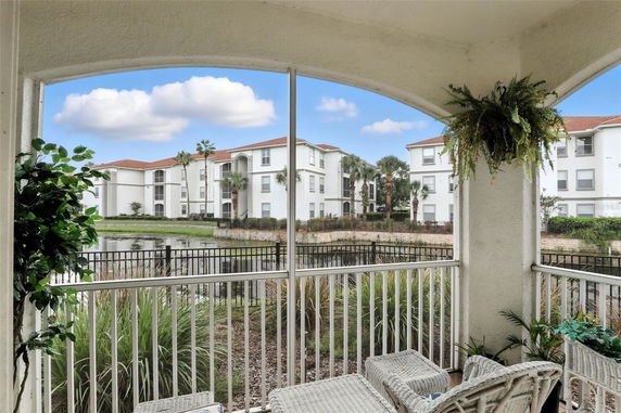View of apartment buildings from a balcony with a fenced pond outside.