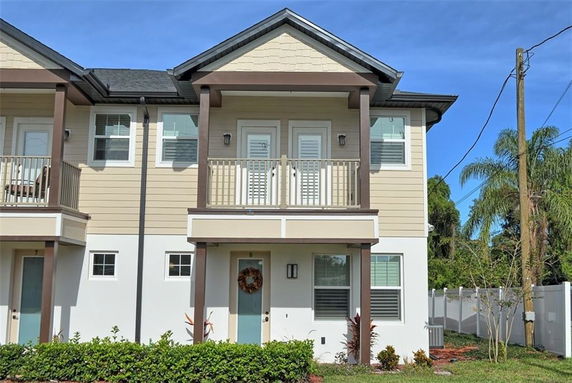 Front view of a two-story townhouse with beige and white exterior, balconies, and a front door wreath.