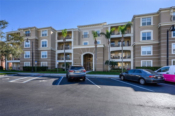 Front view of a multi-story apartment building with balconies and an arched entrance.