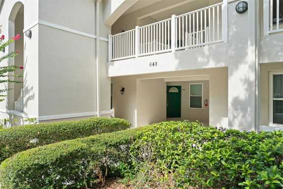 Front view of a two-story building with a balcony and green door.
