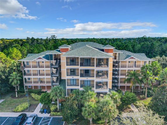 Front view of a four-story apartment building with balconies and a green roof.