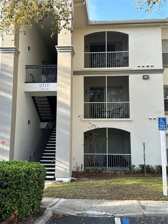 Front view of a three-story residential building with balconies and staircase.
