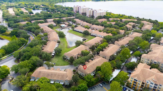 Aerial view of a residential area with multiple buildings surrounded by trees and a water body.