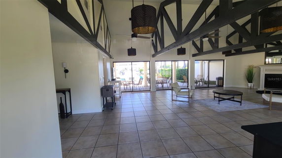 Spacious interior of a club house with high ceilings, exposed beams, tile flooring, and seating area.