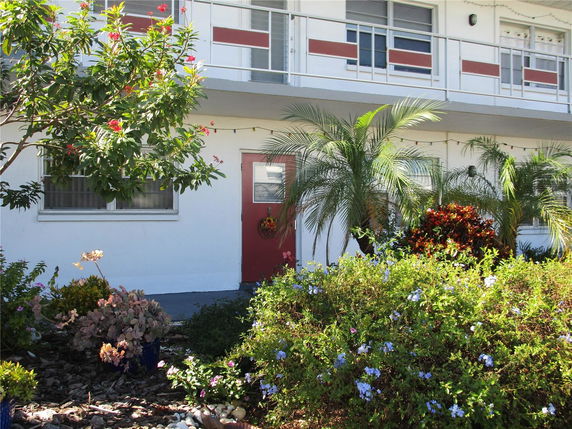 Front view of a two-story building with balconies and a small garden.