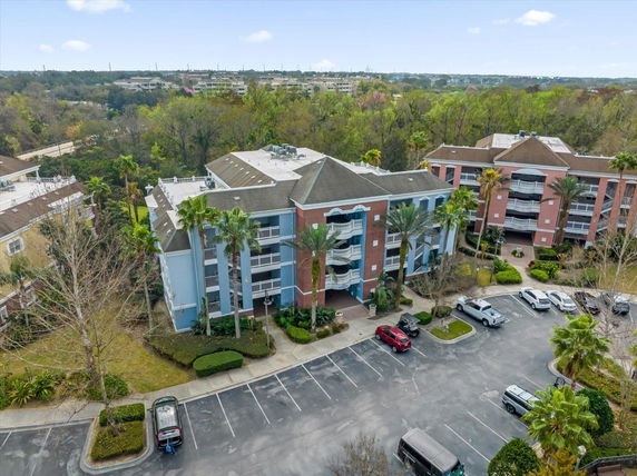 Aerial view of a multi-story residential building with a parking area in front.