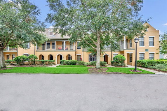 Front view of a two-story building with yellow exterior and arched entryways.