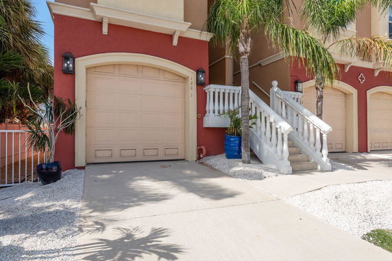Front view of a multi-story house with beige garage doors and decorative white railings.