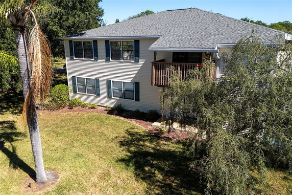 Side view of a two-story house with a balcony and multiple windows.