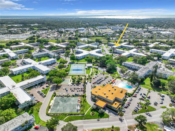 Aerial panoramic view of a residential area with multiple buildings, a swimming pool, and parking lots.