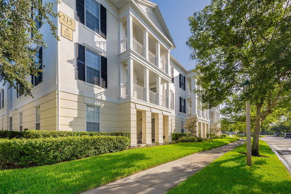 Side view of a three-story residential building with columns and black shutters.